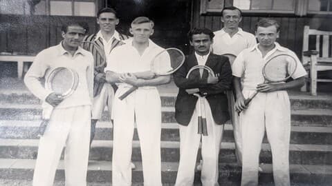 Black white photo of 1946 tennis players, standing with rackets outside Pavillion